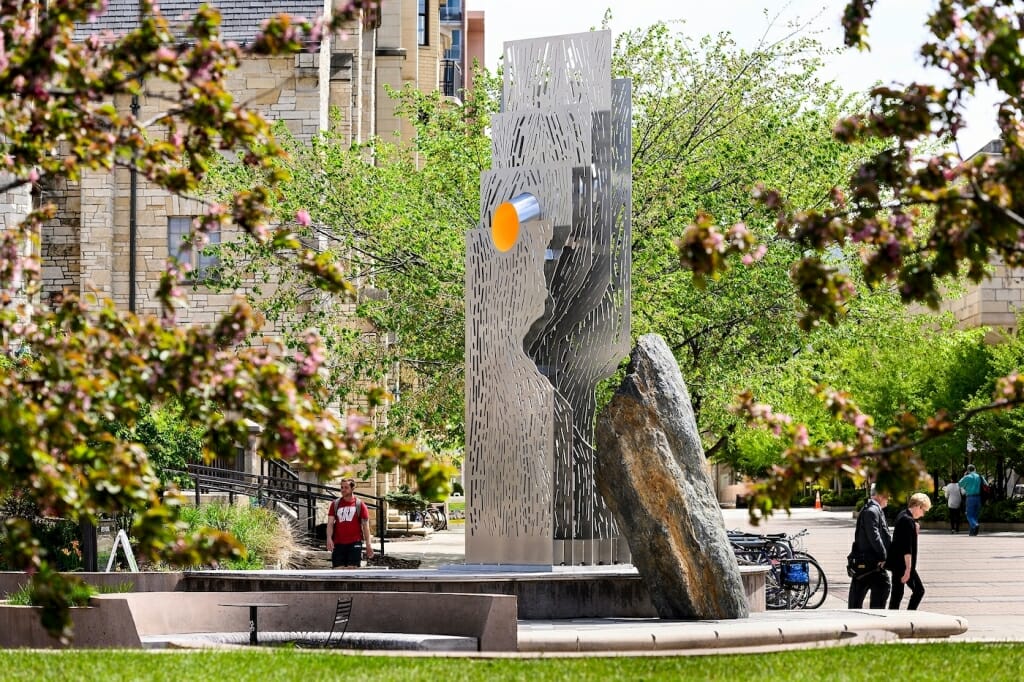 The sculpture is comprised of a large stone leaning in to a vertical stainless-steel sculpture, laser-cut with patterns that allow light to move between the plates.