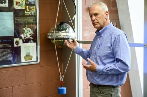 Photo: Bob in lab gesturing to detector