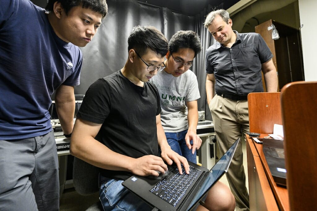 Photo: Four people huddle around a computer.