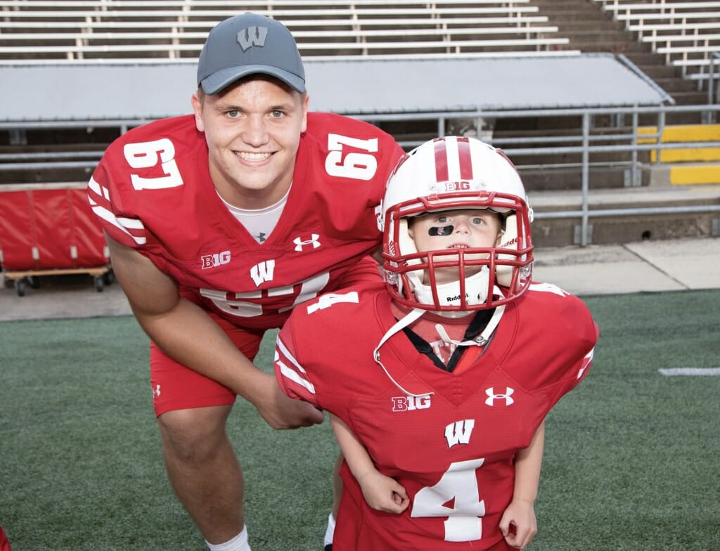 Photo: A player poses with a fan wearing a helmet.