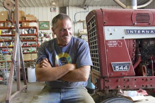 Photo: Paul sitting in building next to tractor