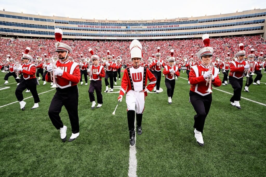 Photo: Drum major with baton surrounded by band members marching