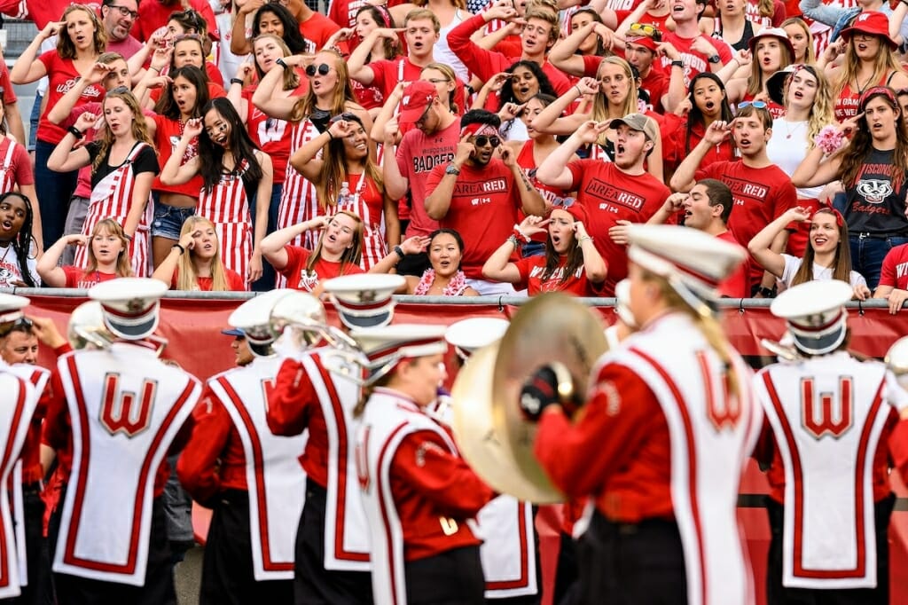 Photo: Fans wearing read standing, singing, and pointing at their heads