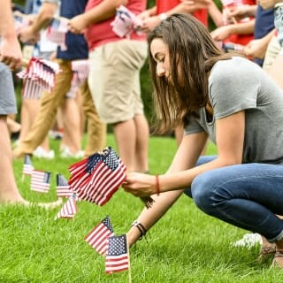 Photo: A woman puts an American flag in the ground.