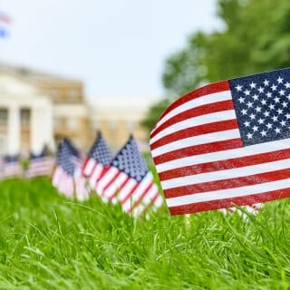 Photo: A lineup of small American flags with Bascom Hall in the background.