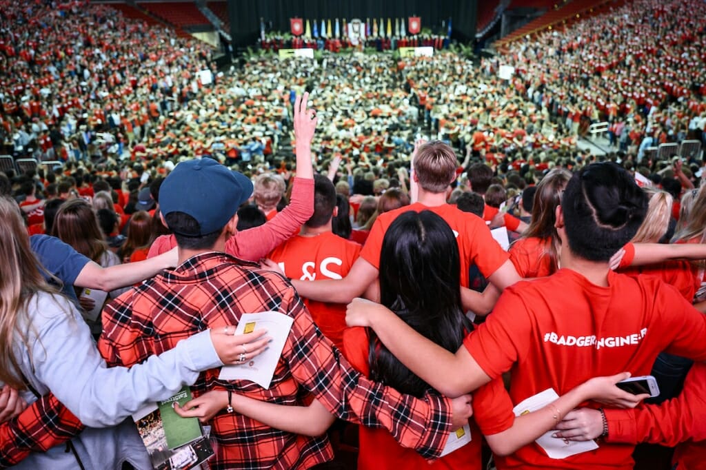 Photo: Students seen from behind with arms around shoulders