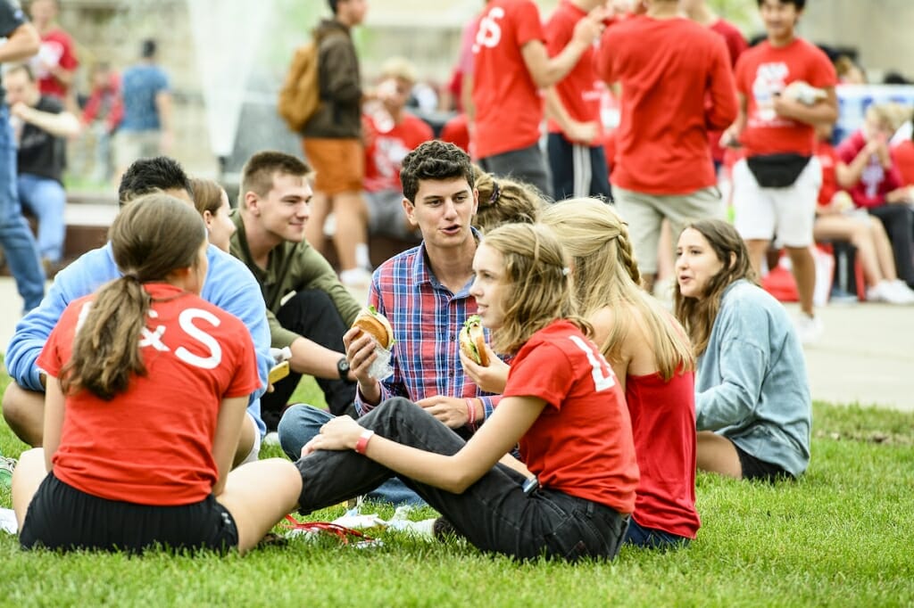 Photo: A group of students sit on the grass and eat.