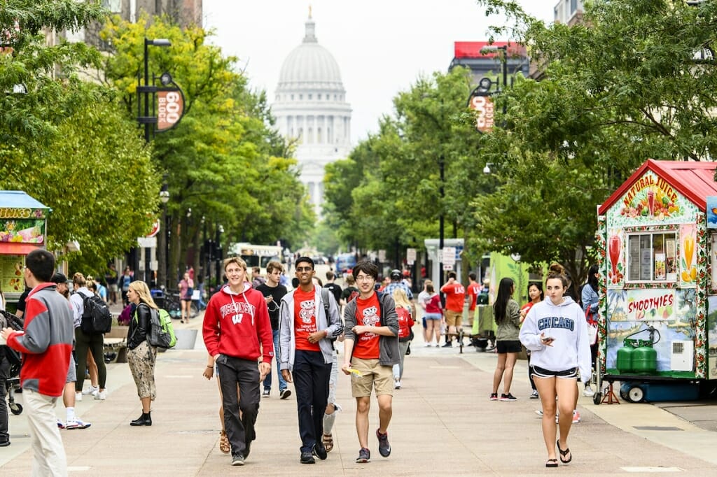 Photo: Three students walk down a crowded library mall.