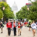 Photo: Three students walk down a crowded library mall.