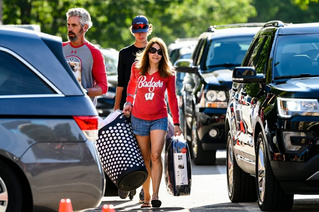 Photo of Parked vehicles lining the road as two parents help move their new student into one of the southeast residence halls.