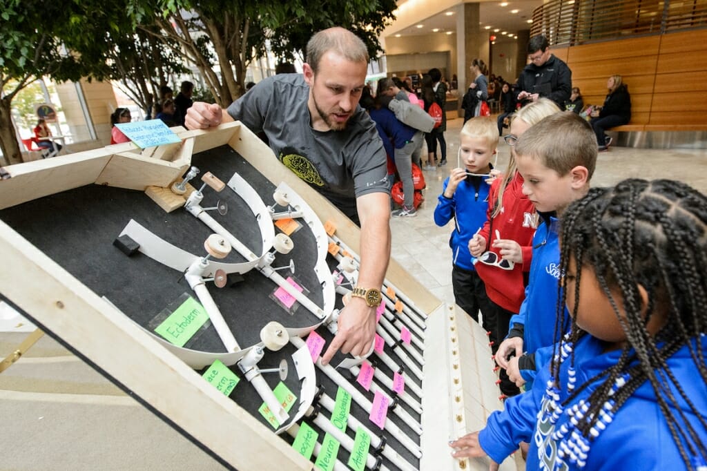 Photo: College student showing children an exhibit