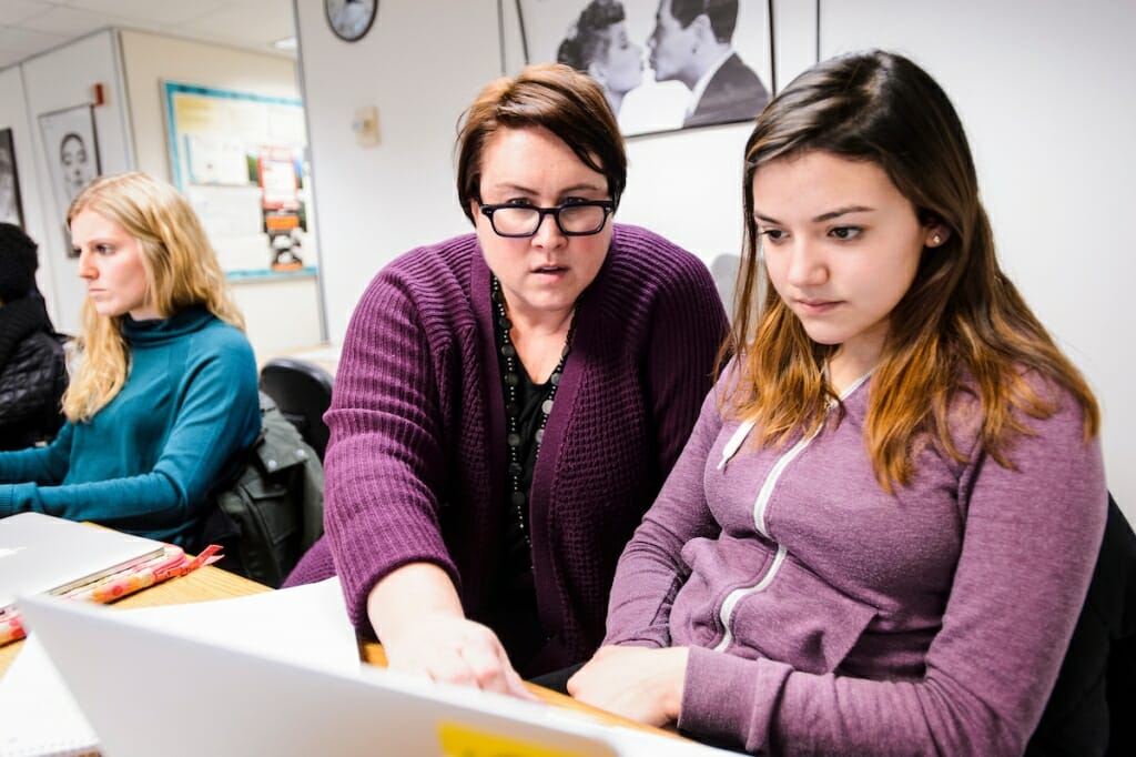 Photo: Skop pointing at laptop as student next to her watches