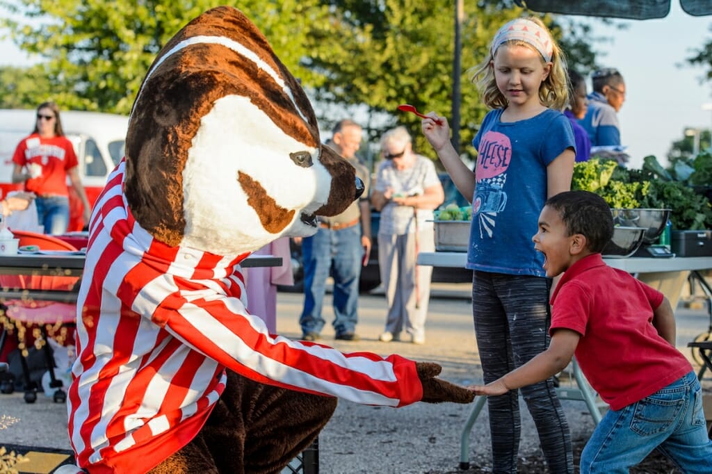 Photo: Young participant smiling while touching Bucky's paw