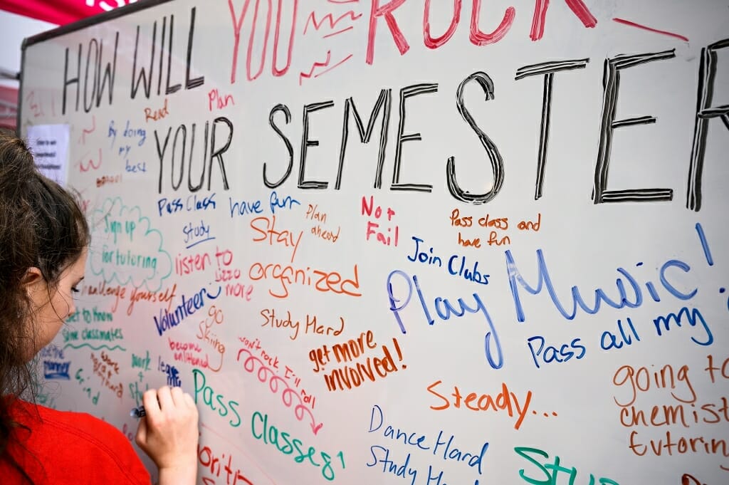 Photo: Person writing with a marker on a whiteboard full of comments in various colors