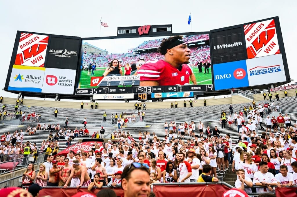 Fans cheer as the video scoreboard shows Wisconsin running back Jonathan Taylor (23) as he walks off the field. Taylor ran for 203 yards and two touchdowns during the game. 