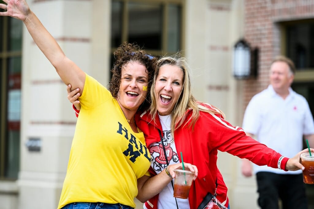 A woman wearing Michigan's maize and blue, and a woman wearing Wisconsin red