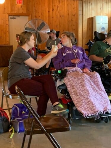 Photo: A caregiver helps feed a person in a wheelchair.