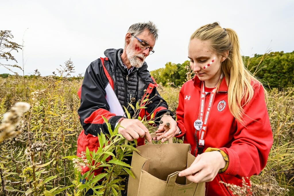 Photo: Man putting seeds into a paper bag held by his daughter