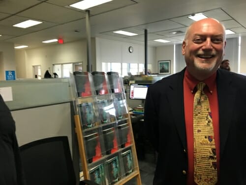 Photo of Press Director Dennis Lloyd standing next to some of the press's publcations