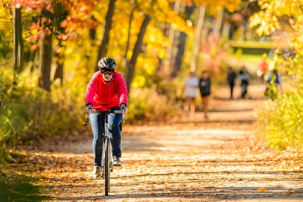 Photo: Bicyclist riding on path through trees with fall colors