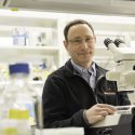 Photo: Newmark standing at microscope in lab