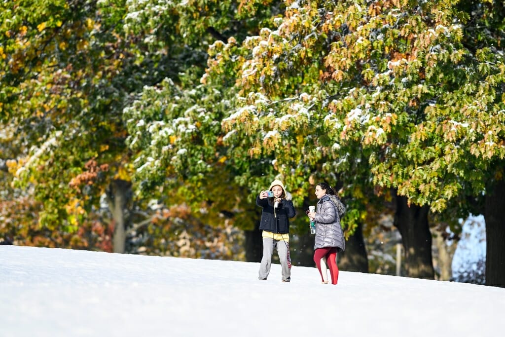 Photo: Two women huddle around a cellphone in the snow.