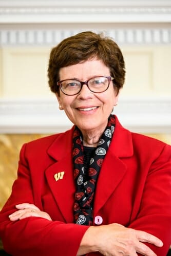 UW-Madison Chancellor Rebecca Blank, wearing a red blazer with a "Motion W" pin, is pictured in her office at Bascom Hall.