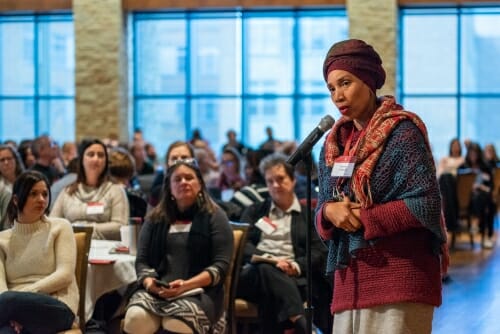 A woman stands at a microphone, asking a question.