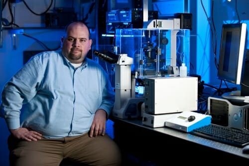 Photo: Eliceiri sitting next to a microscope in a lab