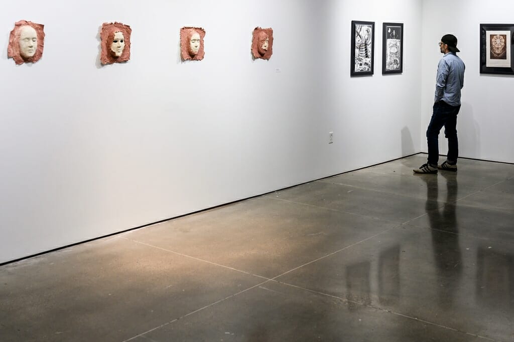 Photo: A person examines a painting on the wall.