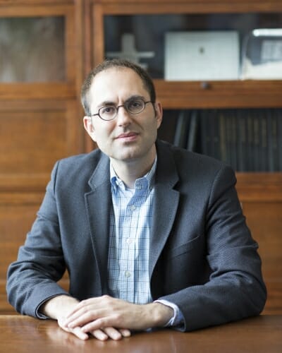 Photo: Portrait of Joshua Coon sitting behind a table