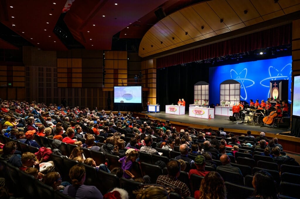 Photo of the audience and the scientists onstage with their equipment