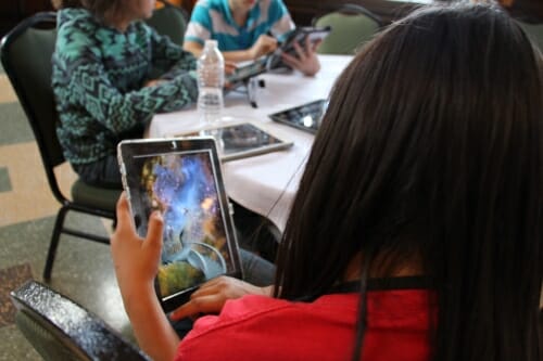 Photo: Child holding tablet computer with game shown on screen