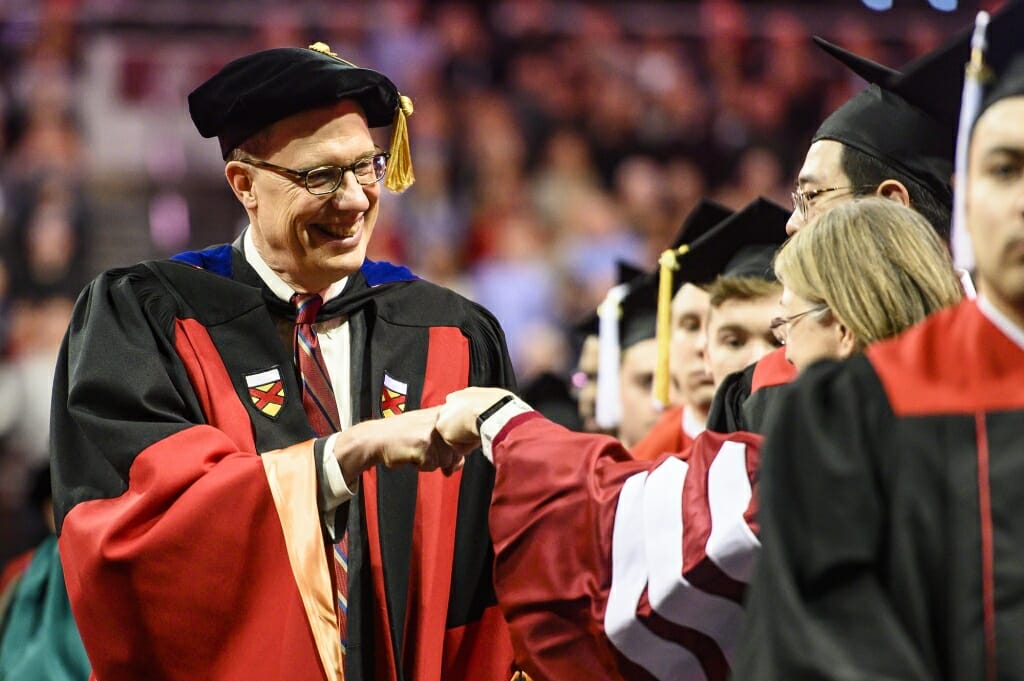 Photo of Provost Karl Scholz bumping fists with a marshal.