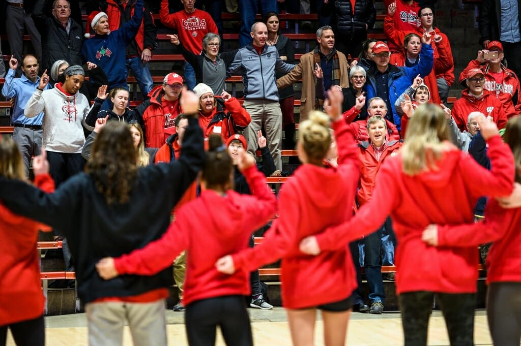 Photo: Volleyball team members clad in red sing arm in arm.