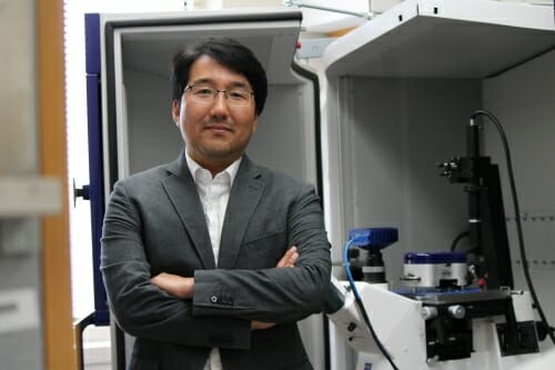 Photo: Portrait of Seungpyo Hong standing in his lab with arms folded