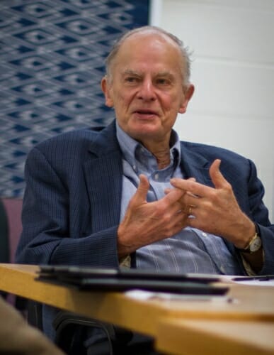 Photo: M. Crawford Young seated at a table in a classroom