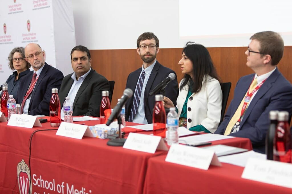 Photo: Safdar speaking at head table, flanked by other panelists