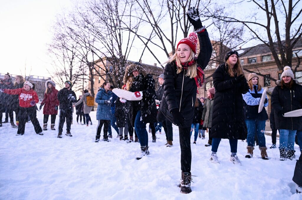 A person balanced on one leg after throwing a snowball