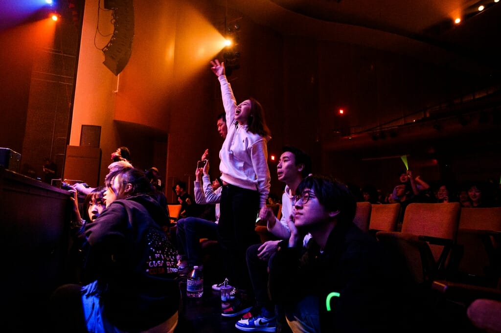 Audience members jump up and wave their arms.