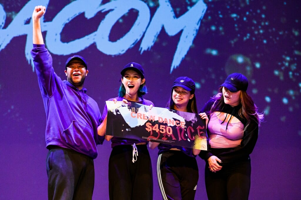 Dancers hold up a sign.