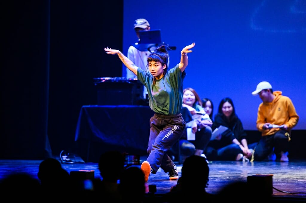 A female dancer raises her arms.