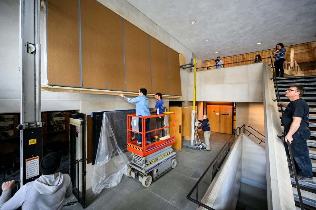 Workers on a lift prepare the mural.