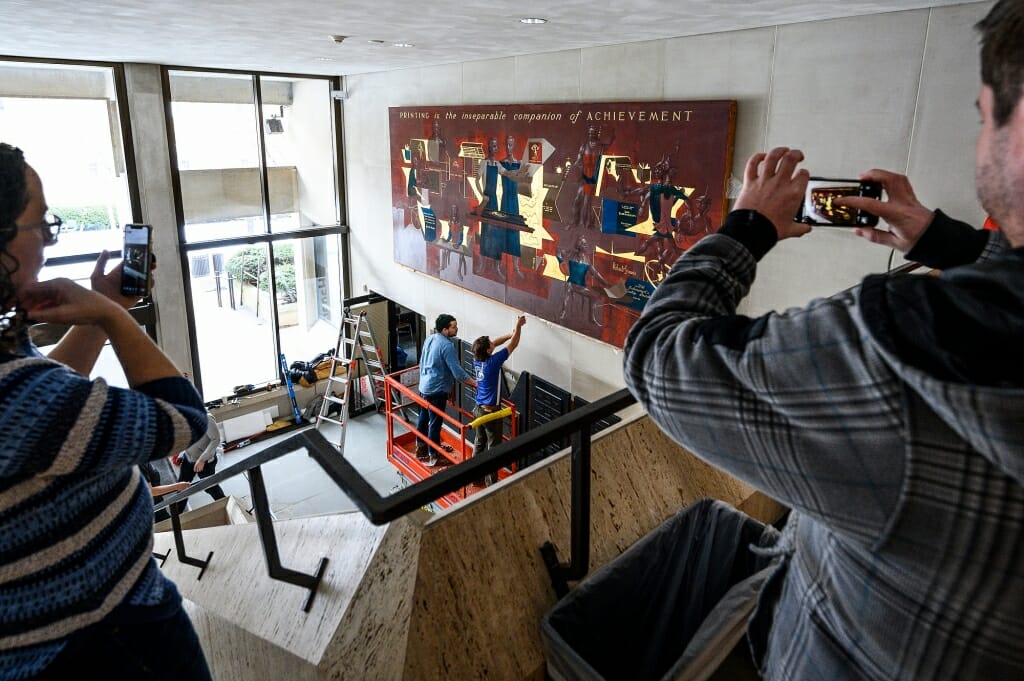 Two people use their phones to record the installation process.