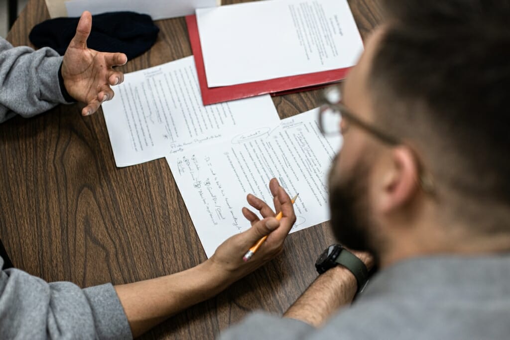 Closeup of marked-up draft of an essay being examined by 2 unidentified people