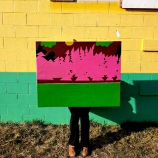 Painting being held in front of yellow and green wall