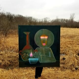 Painting being held in front of field of brown grass and bare trees