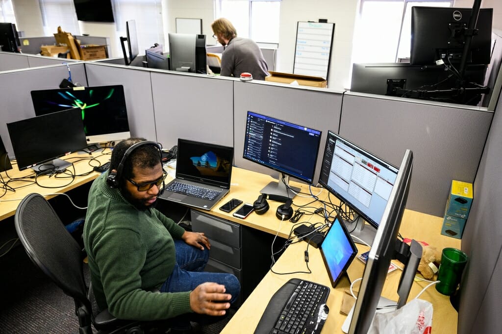 Two men work at desks in a large room.