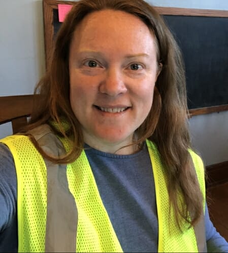 Woman sitting in chair wearing green neon safety vest