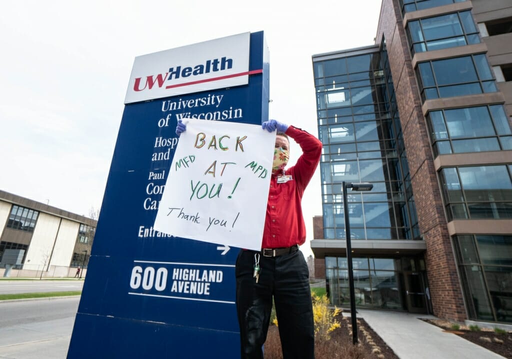 Man in mask holding sign that says BACK AT YOU! MFD MPD Thank you!